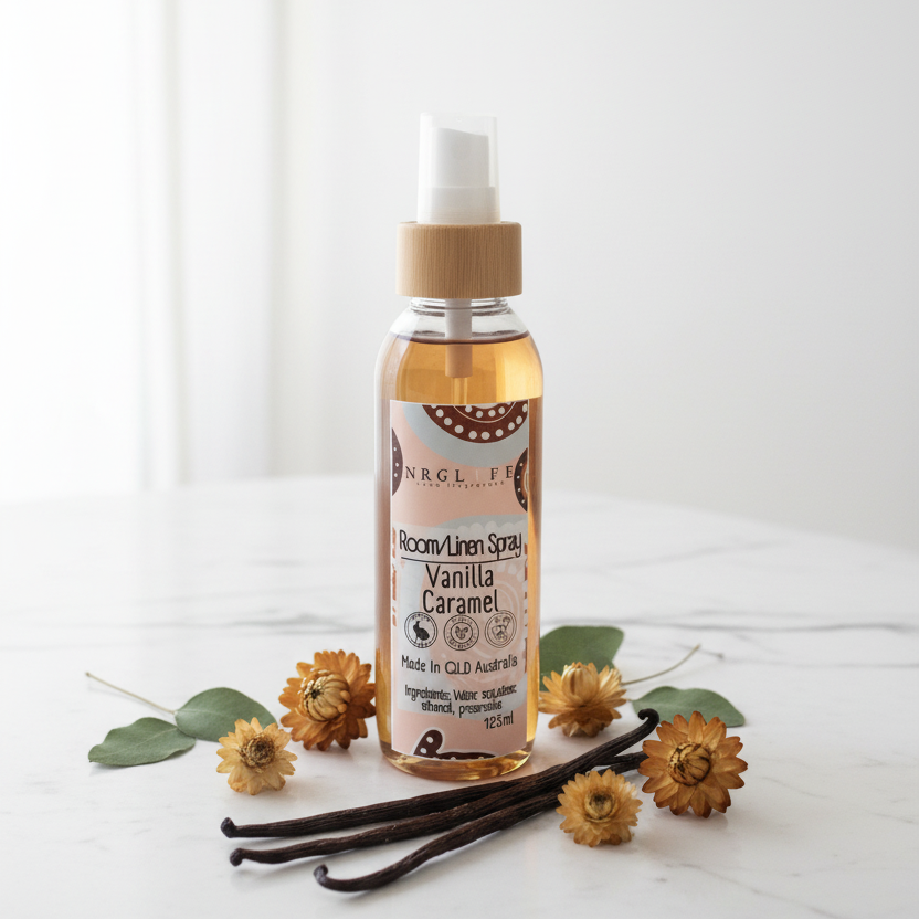 Vanilla Caramel Room Linen Spray bottle with vanilla beans and flowers on a white background