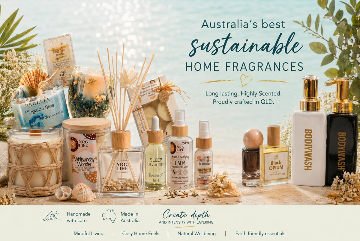 A styled product lineup of sustainable home fragrances and personal care items arranged on a beach-themed backdrop. Visible products include a reed diffuser, candles, spray bottles, a black body wash bottle, and a white body wash bottle, with text reading 'Australia's best sustainable home fragrances' and brand names such as Bodywash, Calm, and Sleep Well.