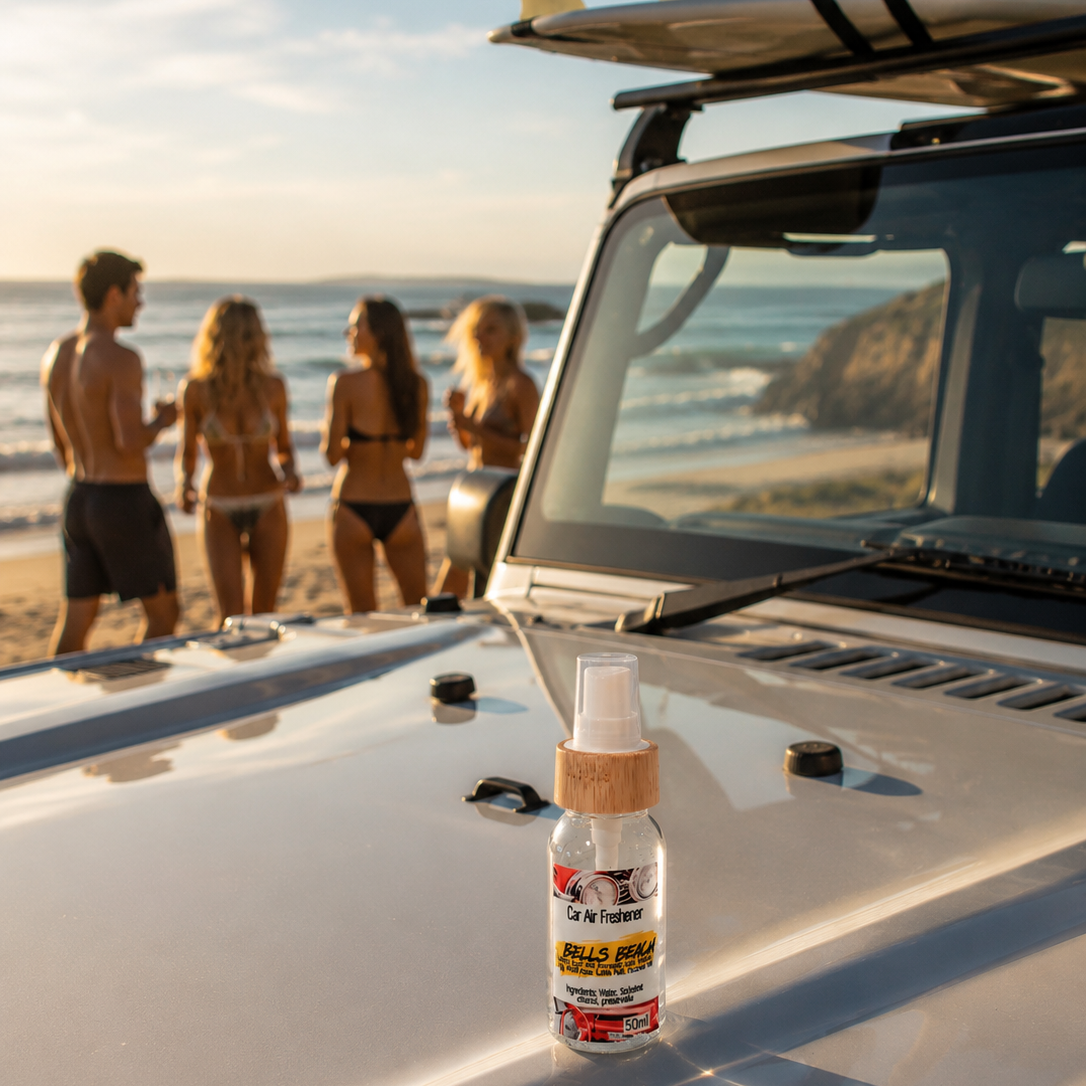 Bells Beach Car Air Freshener sitting on the bonnet of a grey jeep with surfboards on the roof rack with people gathered at the beach in the background. 