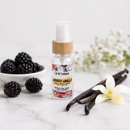 Berry Vanilla car air freshener bottle sitting on a marble table with flowers in the background.