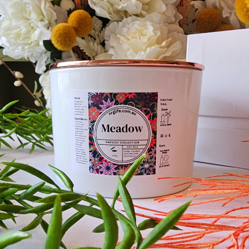A Large white candle infused with our floral fragrance Meadow, featured with Rose Gold Lid on top.