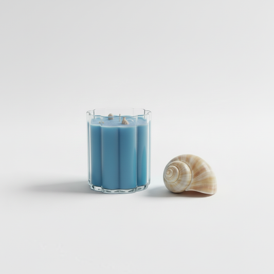 Blue candle in a glass container shaped like a cloud with a shell on a white background