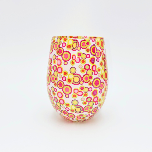 A candle jar with small coloured circle patterns all over in pink green, yellow and mauve.
