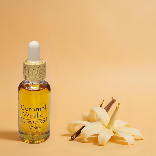 Diffuser bottle of Caramel Vanilla fragrant oil blend with vanilla flowers on a beige background.