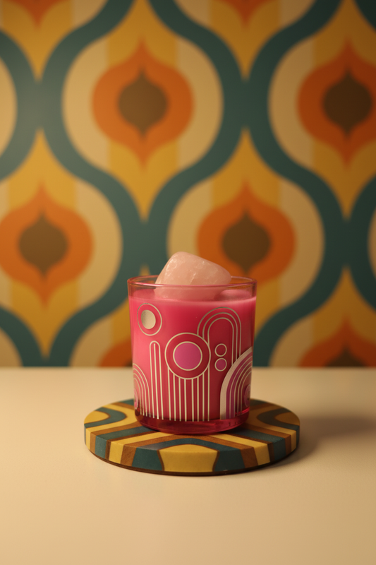Art Deco Candle sitting on a heat proof plate with pink coconut soy wax with a rose quartz crystal in it with art deco wall paper behind.