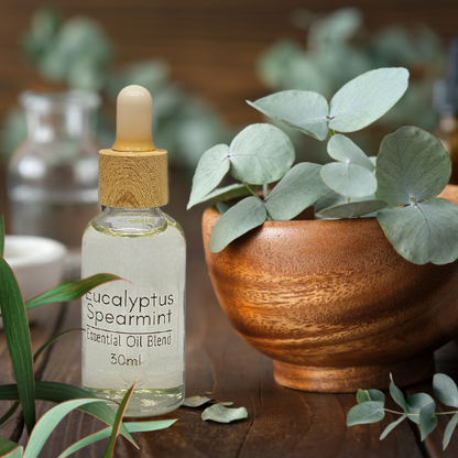 30ml Eucalyptus Spearmint essential diffuser oil blend sitting on a timber table with eucalyptus leaves in a wooden bowl beside it.