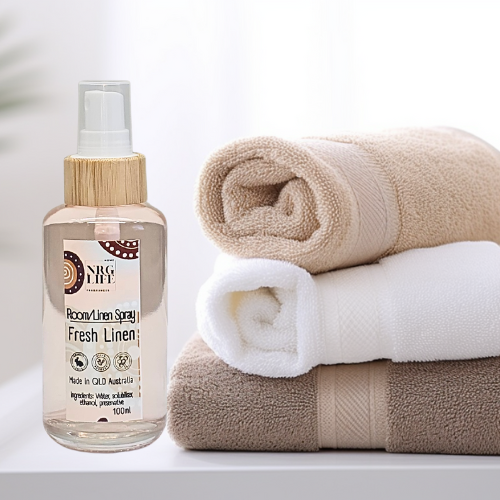 Room linen spray called 'fresh linen' bottle with rolled towels on a white background