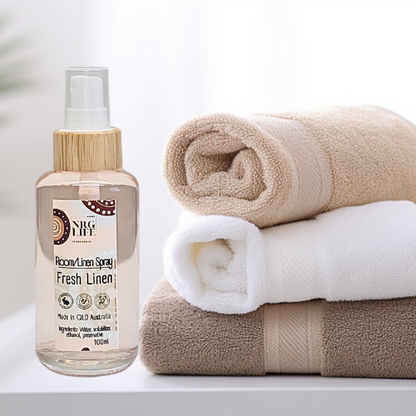 Room linen spray called 'fresh linen' bottle with rolled towels on a white background