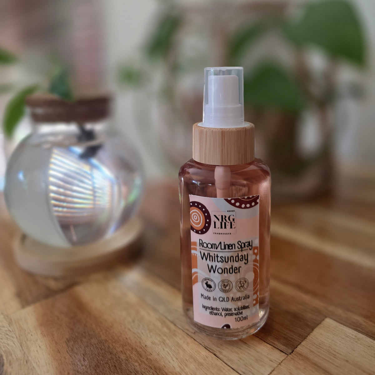 100ml Glass Bottle of Room Linen Spray with the fragrance Whitsunday Wonder, pump spray on a wooden surface with a blurred background.