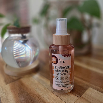 100ml Glass Bottle of Room Linen Spray with the fragrance Whitsunday Wonder, pump spray on a wooden surface with a blurred background.
