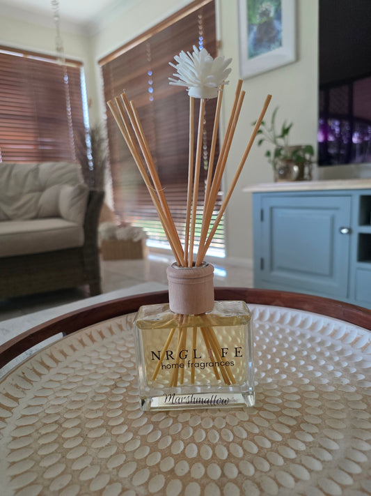 Marshmallow reed diffuser on a textured surface with a blurred indoor background.