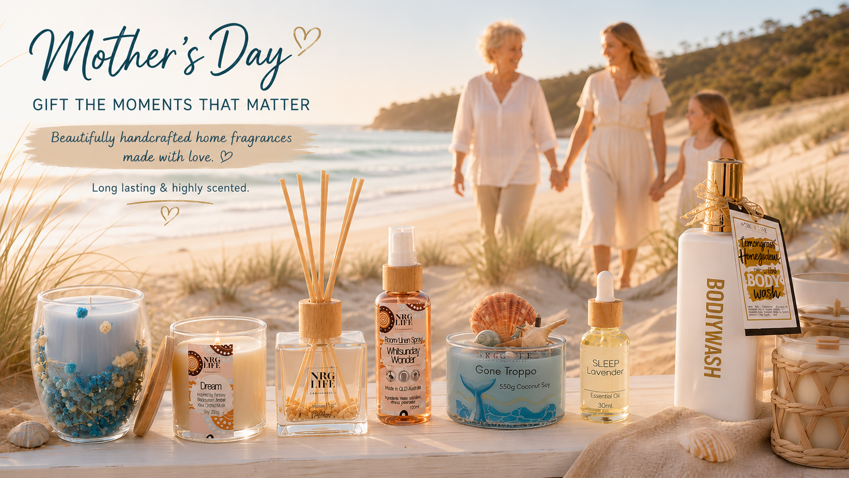 Gift idea candles room sprays diffusers and body wash on timber sitting on the sand at the beach with three generations of women walking along.
