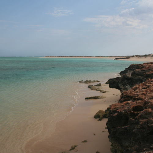 A photograph of where the water meets the red sands at the Ningaloo Coastline, WA.
