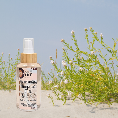 Room linen spray bottle labeled 'Ningaloo Bliss' on a sandy background with plants.