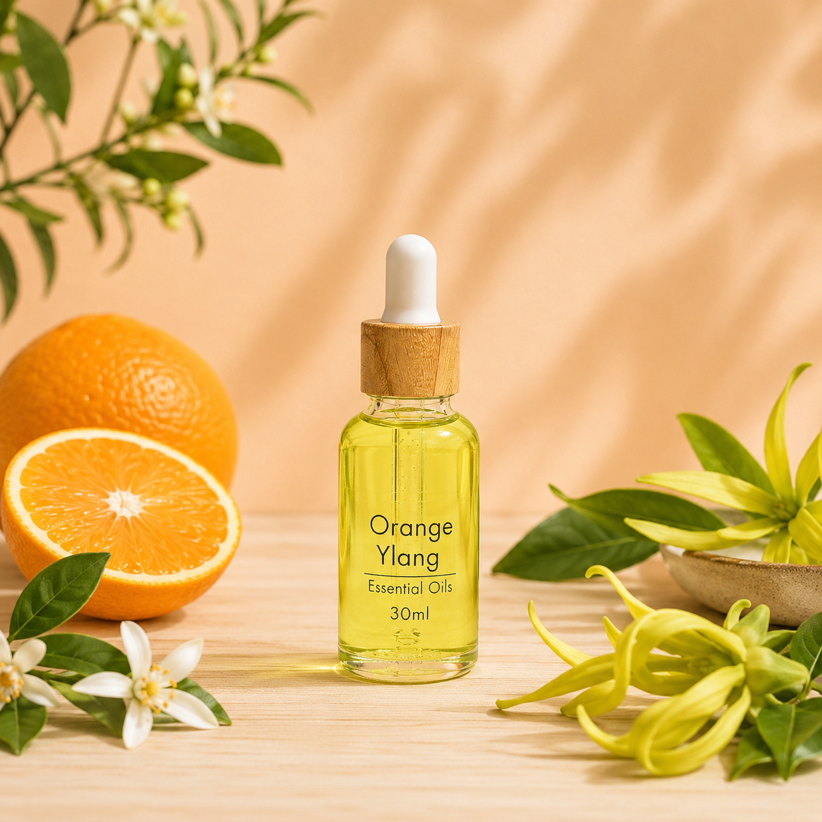 30ml Orange & Ylang Diffuser 'Essential Oil' bottle with dropper, sitting on a light timber table with filtered light fresh orange and ylang sprigs.