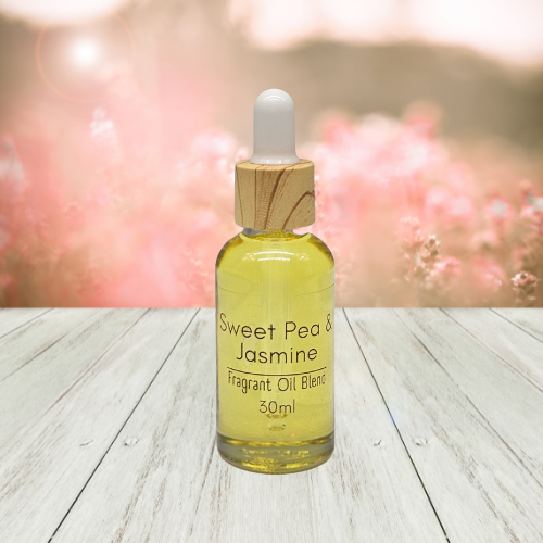 30ml Bottle of Sweet Pea & Jasmine diffuser fragrant oil blend on a wooden surface with a blurred floral background.