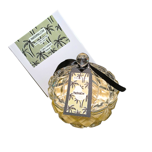 An extra large diamond shape glass candle with matching lid with marshmallow fragrance. It has a black ribbon attached to the label. Candle has an example box on the side with a white background.
