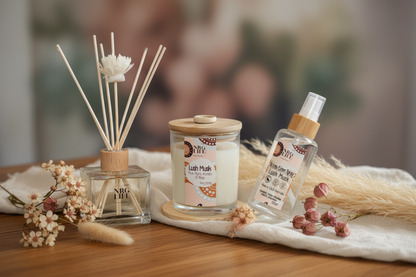 Best Seller Aromatherapy products including a diffuser, candle, and room spray in the scent Lush Musk on a wooden surface with a blurred background.