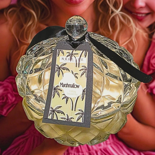 Mum with children standing behind, wearing pink holding an extra large diamond shape glass candle with matching lid and marshmallow fragrance.